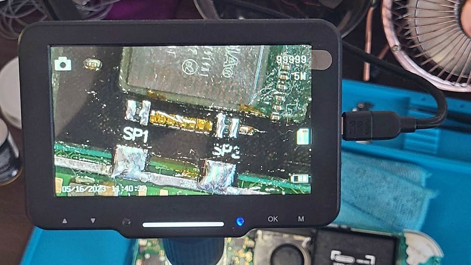 Microscope view of soldered points labeled SP1 and SP2 on a Switch board